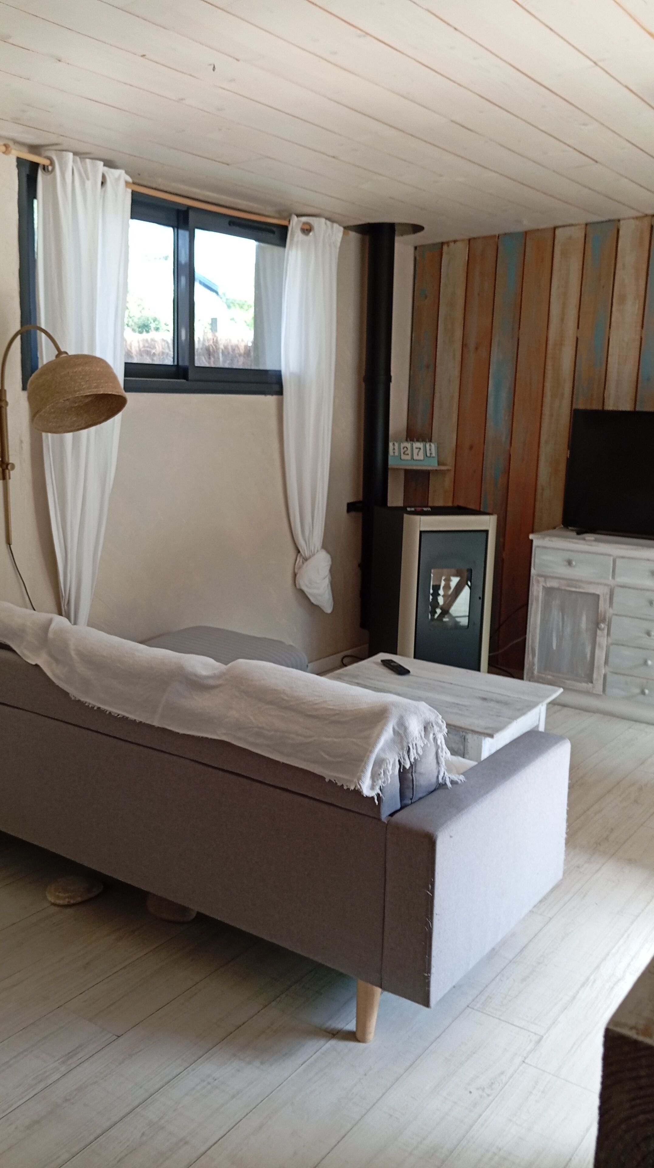 Um quarto com uma cama, uma luminária, uma televisão e um armário.