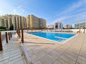 A swimming pool with a tiled deck, surrounded by high-rise residential buildings. - Apartment Praia Rocha | Sea View | Prestige (Portimão)