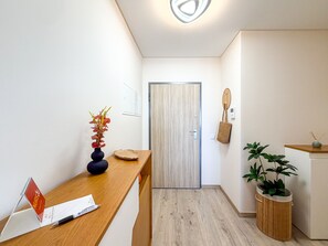 Ein moderner Flur mit einem Holzbüro, einer Tür, einer Wandtasche und einem Blumentopf.