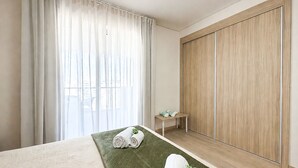 Hotelkamer met een bed, een groen tapijt met structuur, een houten kledingkast en een tafeltje met handdoeken.