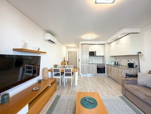 A modern living room with a flat-screen TV, wooden coffee table, and a sofa. - Apartment Praia Rocha | Sea View | Prestige (Portimão)