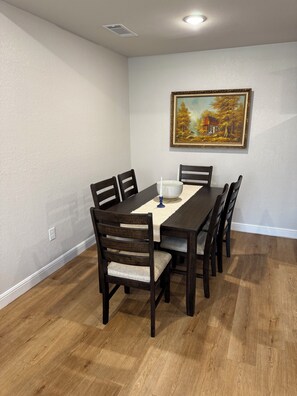 A dining room with a wooden table, six chairs, and a painting on the wall. - Newly Updated 2BR/2BA • King Suite • Near ACU (Abilene)