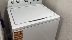 A white Whirlpool washer in a corner with wooden cabinets above. - Newly Updated 2BR/2BA • King Suite • Near ACU (Abilene)