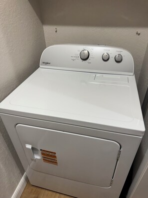 Eine Whirlpool Waschmaschine in einem Waschraum, mit Bedienfeld und Warnhinweis an der Tür.
