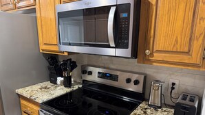 A kitchen with a stainless steel microwave, a black stove, and a granite countertop. - Newly Updated 2BR/2BA • King Suite • Near ACU (Abilene)