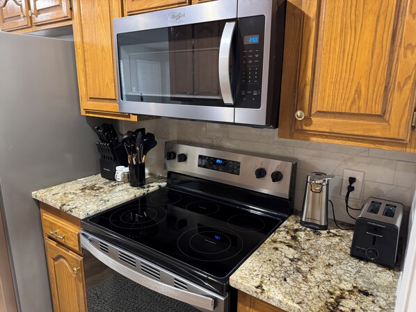 A kitchen with a stainless steel microwave, a black stove, and a granite countertop. - Newly Updated 2BR/2BA • King Suite • Near ACU (Abilene)