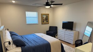 A bedroom with a bed, dresser, chair, TV, and ceiling fan. - Newly Updated 2BR/2BA • King Suite • Near ACU (Abilene)
