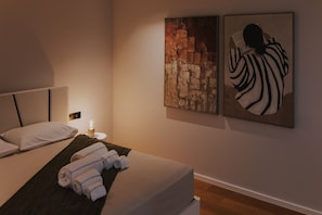 A hotel room with a bed, a nightstand with a lamp, and two artworks on the wall. - Villa Nero – Private Luxusvilla mit beheizbarem Pool & Atlantikblick (Arco da Calheta)