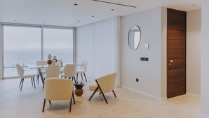 Un interior moderno con zona de comedor, ventanas amplias y una puerta de madera.