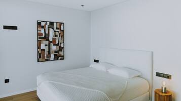 A modern bedroom with a large bed, a wall-mounted abstract art piece, and a bedside table with a lamp.