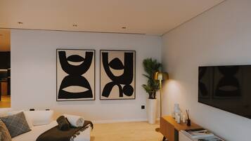 Un salon moderne avec un canapé, une table basse, une plante et deux tableaux abstraits accrochés au mur.