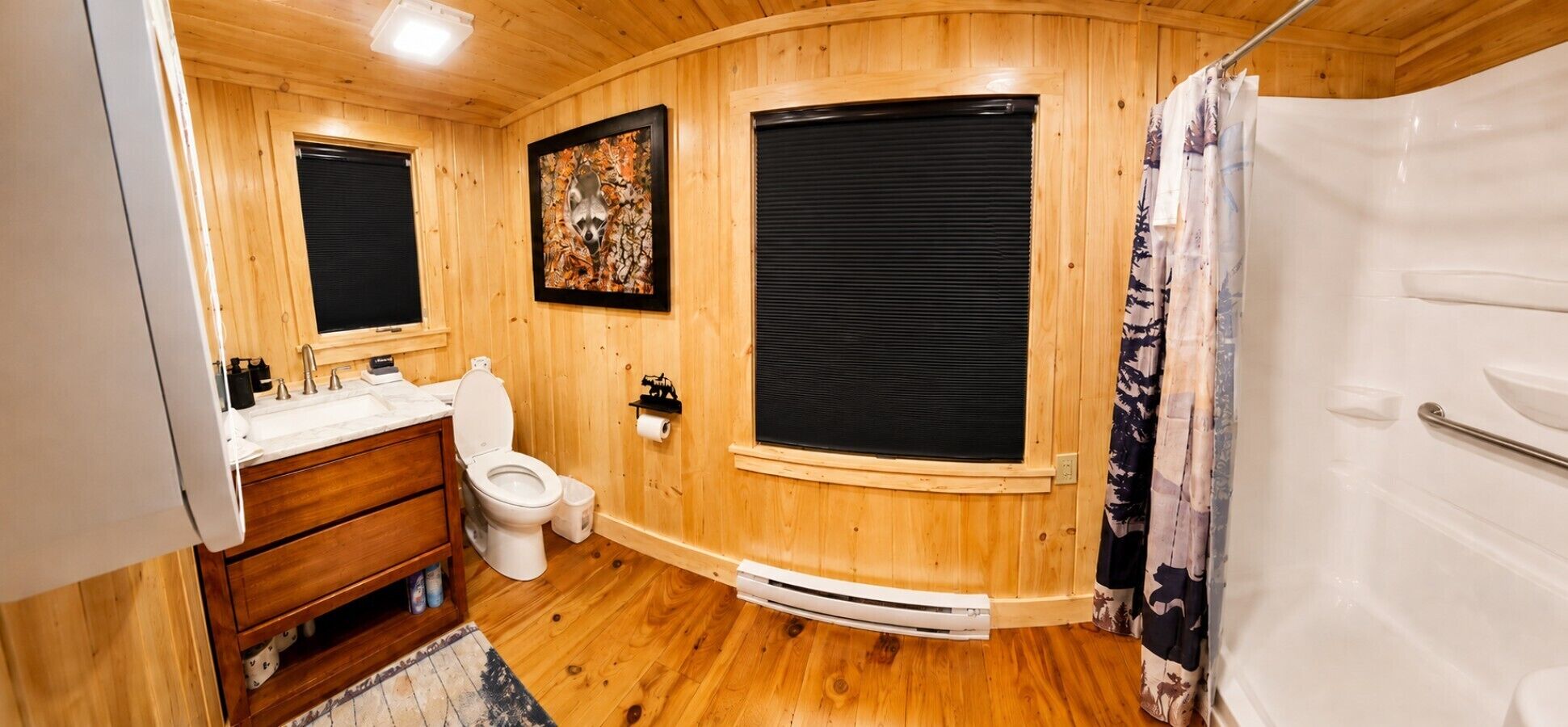 Ein Badezimmer mit Holzwänden, einer Toilette, einem Waschbecken und einer Dusche.