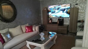A living room with a sofa, coffee table, TV, and a cabinet with items on top. - Modern Private Suite with Pool, Kitchen & Ensuite (Khémisset)