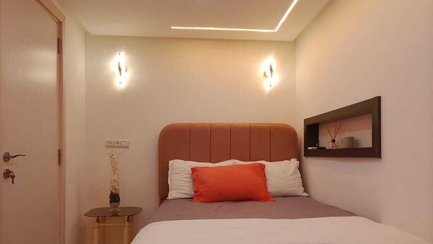 A bedroom with a bed, bedside table, wall-mounted light, and a framed picture. - Modern Private Suite with Pool, Kitchen & Ensuite (Khémisset)