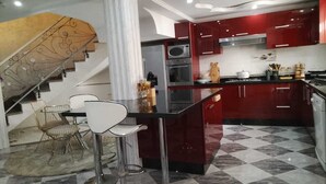 A modern kitchen with red cabinets, a marble floor, and a glass dining area. - Modern Private Suite with Pool, Kitchen & Ensuite (Khémisset)