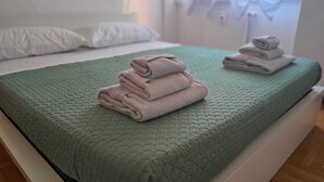 Una cama con un edredón verde y toallas dobladas.
