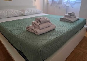 Ein Bett mit einer grünen Steudecke und gefalteten Handtüchern.