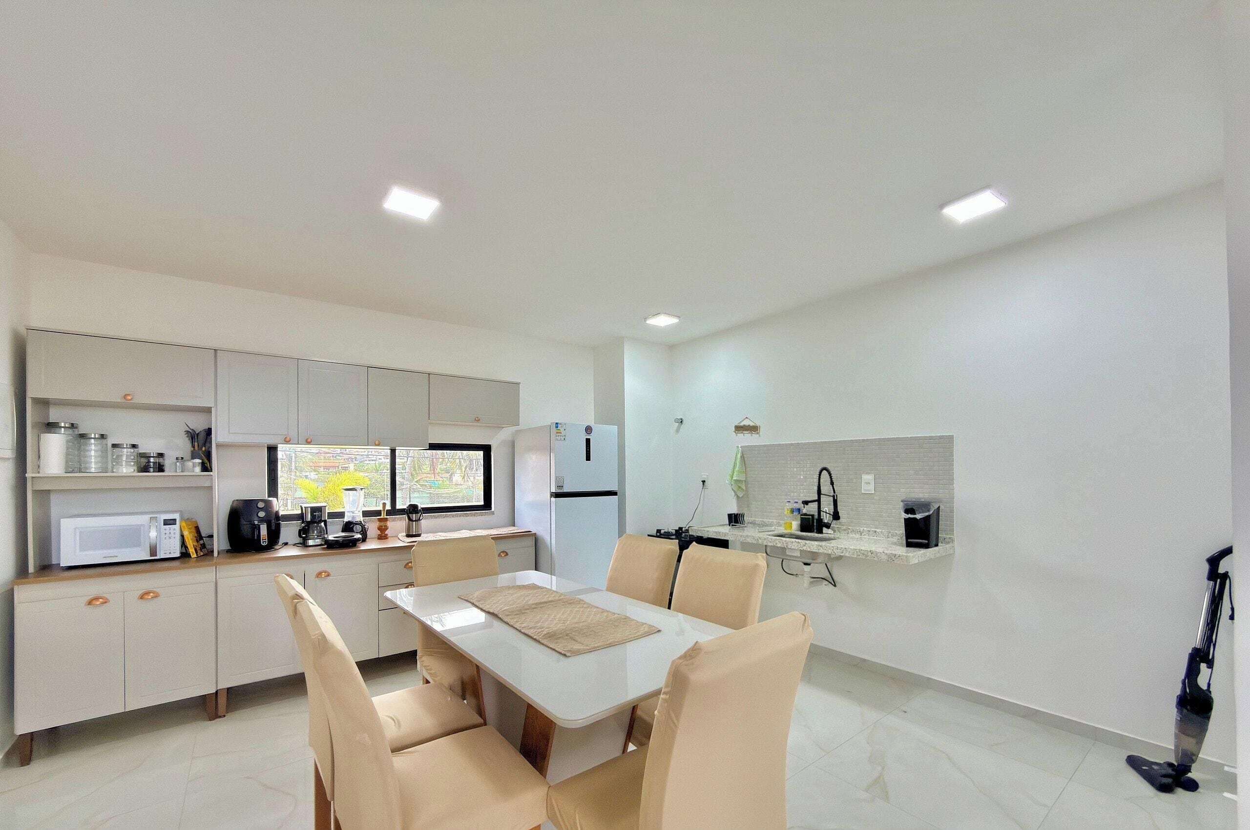 A compact kitchen with a dining area, equipped with a microwave, coffee maker, and a refrigerator.