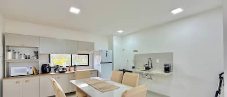 A compact kitchen with a dining area, equipped with a microwave, coffee maker, and a refrigerator.