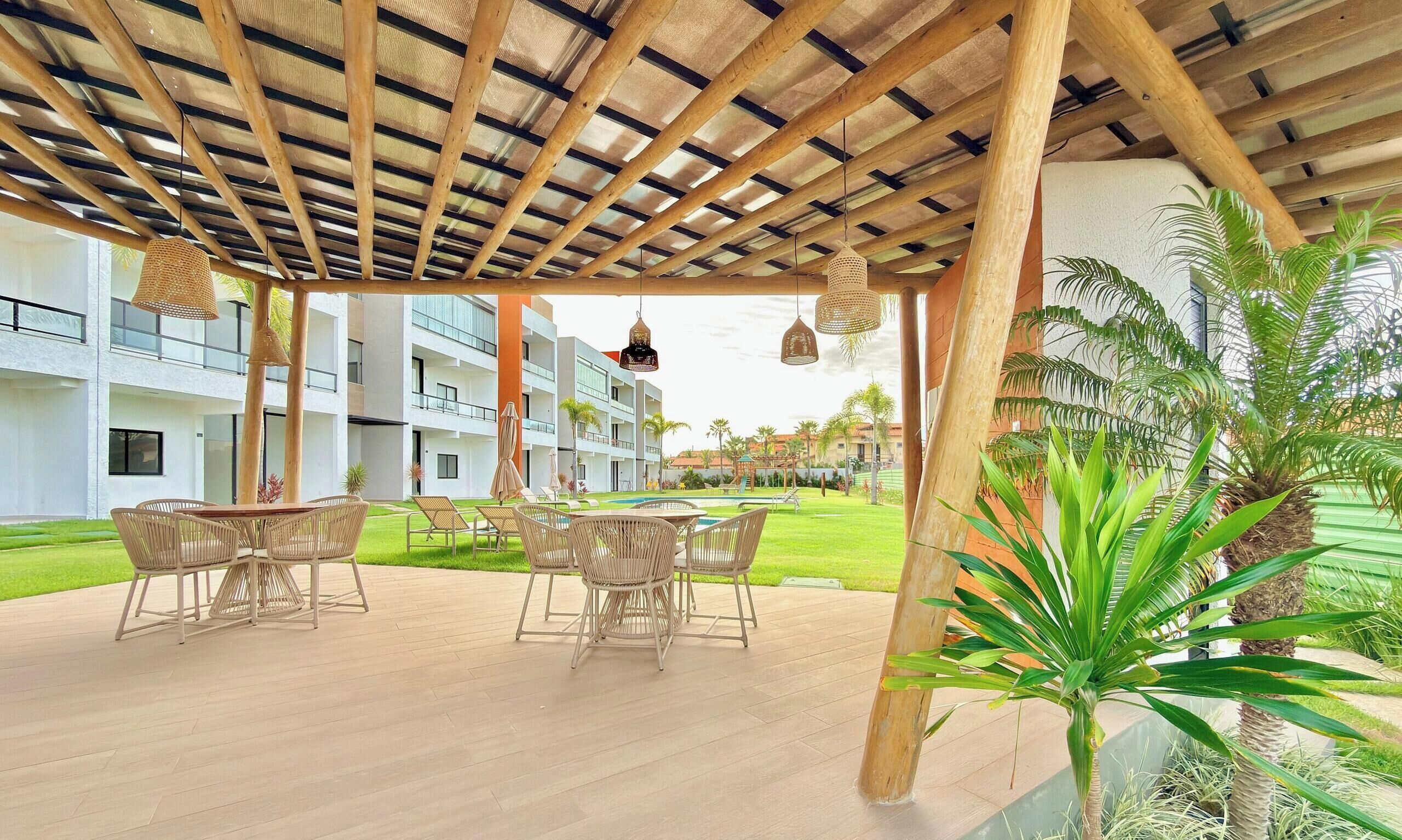 A covered outdoor area with a pool, lounge chairs, and a wooden pergola.
