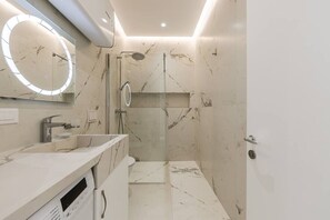 A modern bathroom with a vanity, a shower, and a large mirror. - Sapphire Coast Drymades | Modern 2BR Apartment by PikHost (Dhërmi)