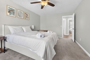 A bedroom with a bed, bedside tables, a ceiling fan, and artwork on the wall. - Elegant 3BR 5-Bed Spacious Home: Pool & Patio (Galloway)