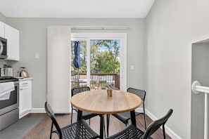A compact kitchen with a dining area, a sliding glass door leading to an outdoor deck. - Elegant 3BR 5-Bed Spacious Home: Pool & Patio (Galloway)