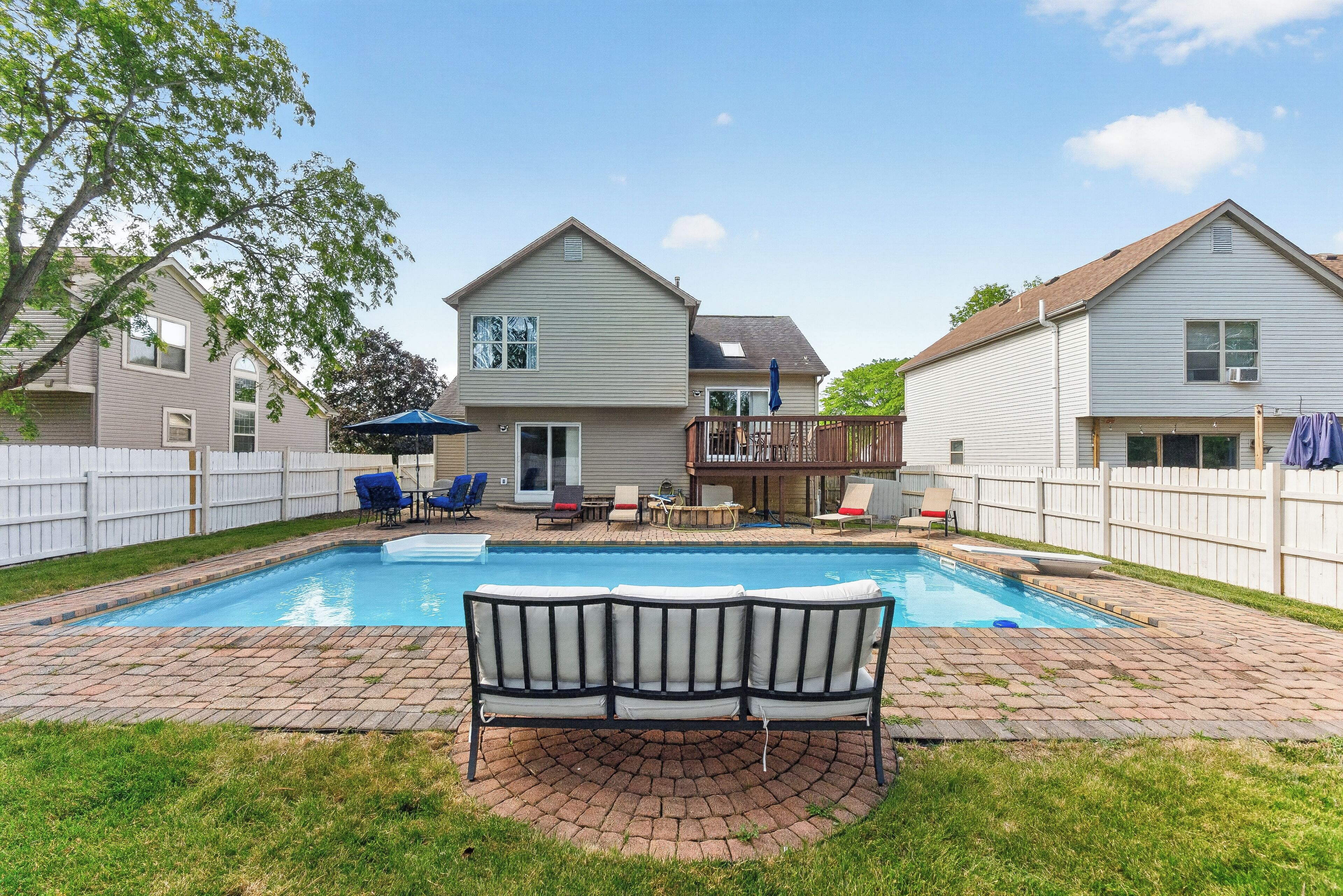 A backyard with a swimming pool, a covered patio area, and a fenced yard.