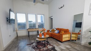 A spacious living room with a large window, a sofa, a coffee table, and a wooden floor. - 2-bedroom apartment in beautiful Dallas with AC and fitness room (Dallas)