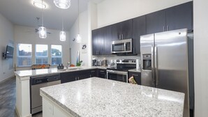 A modern kitchen with granite countertops, stainless steel appliances, and dark cabinetry. - 2-bedroom apartment in beautiful Dallas with AC and fitness room (Dallas)