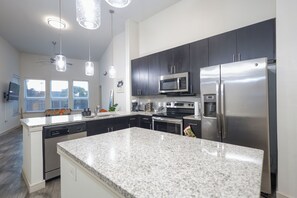 Una cocina moderna con encimeras de granito, electrodomésticos de acero inoxidable y armarios oscuros.