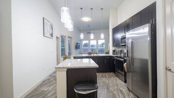 A modern kitchen with a central island, stainless steel appliances, and pendant lighting.