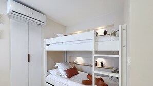 A bunk bed with a white headboard, a shelf with decorative items, and a white wardrobe. - Luma, ocean view, pool, charming, central location (Grand-Case)