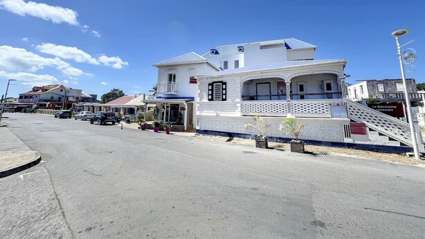 A white building with a balcony and a staircase leading to the entrance. - Luma, ocean view, pool, charming, central location (Grand-Case)