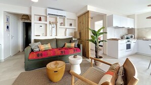 A modern living room with a sofa, coffee table, and a dining area with a kitchen in the background. - Luma, ocean view, pool, charming, central location (Grand-Case)