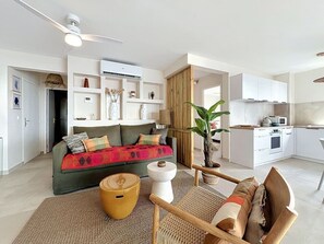 Ein modernes Wohnzimmer mit Sofa, Couchtisch und Essbereich. Im Hintergrund ist eine Küche zu sehen.