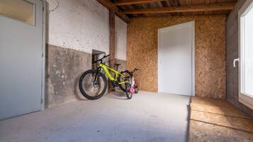 Une pièce avec un plafond en bois, une porte blanche et un vélo appuyé contre le mur.