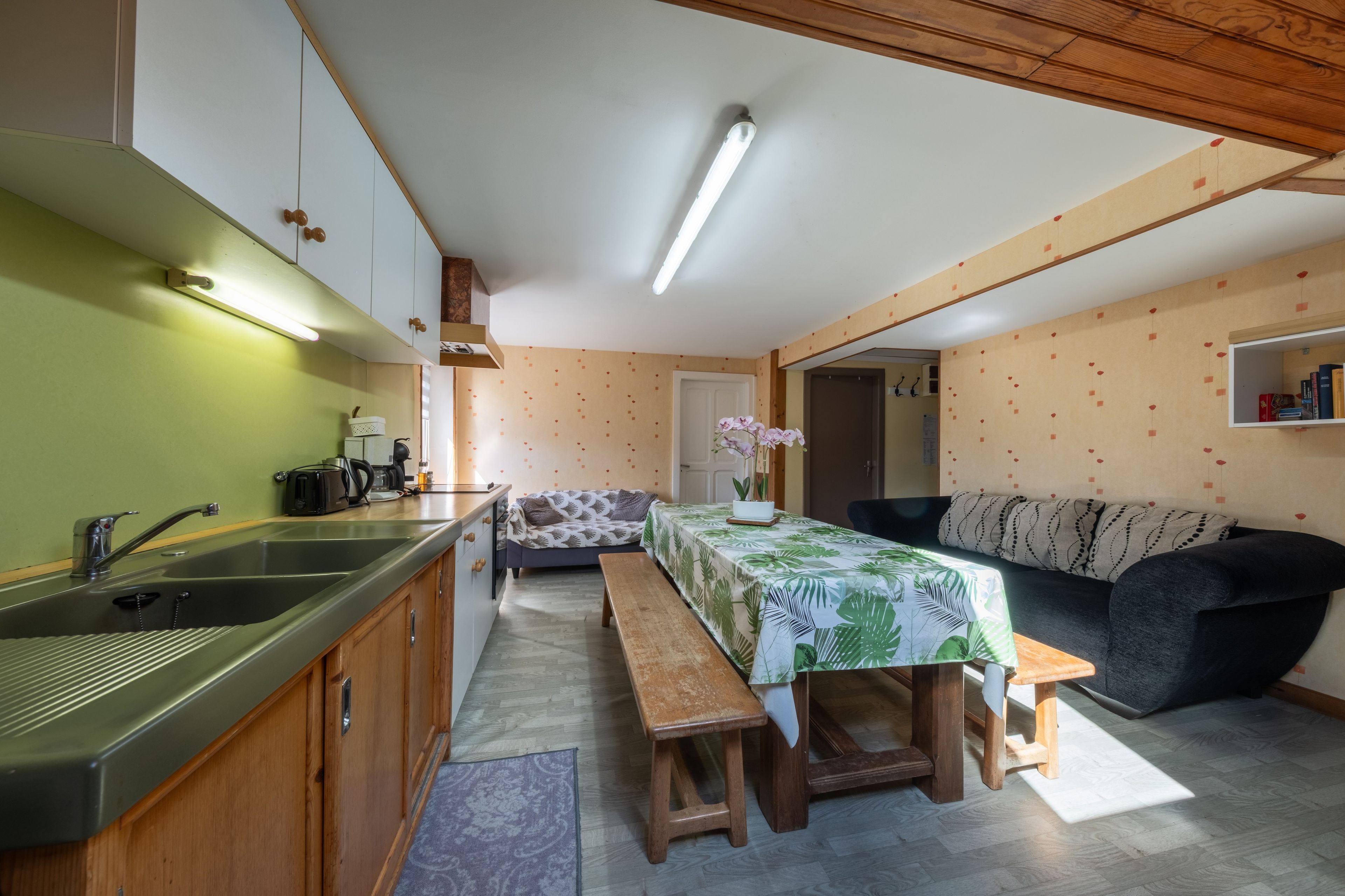 A compact kitchen with a sink, countertop, and wooden cabinets.