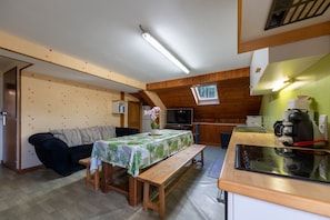 Un espace de vie compact comprenant un coin cuisine, un coin repas avec une banquette et un canapé.