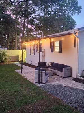A covered patio area with outdoor seating and string lights. - Charming 2-bedroom house in Oak Island close to the beach (Oak Island)