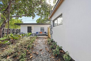 Ein modernes Haus mit einer Terrassenanlage, einem grauen Sofa und einem kleinen Tisch.