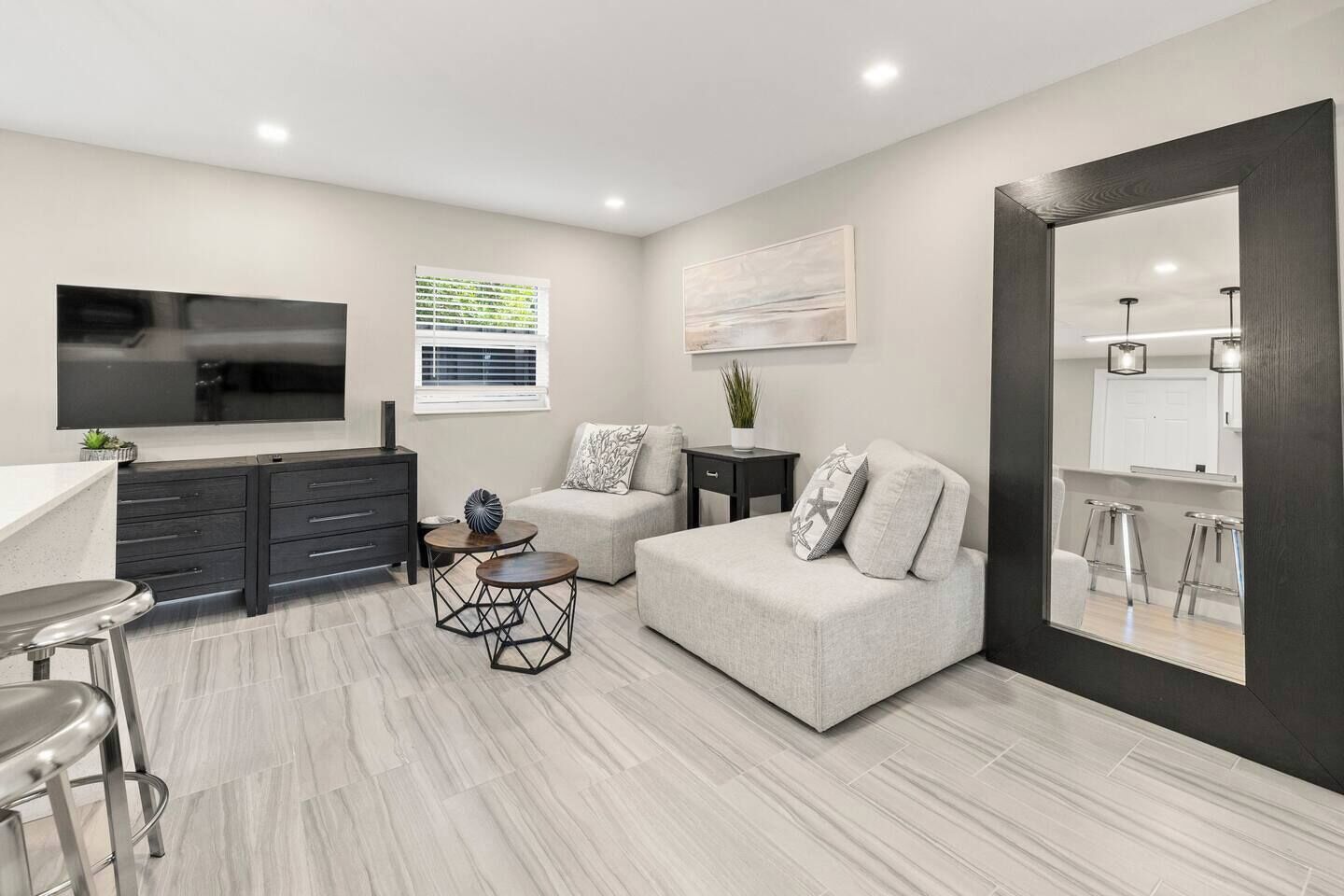 A modern living room with a sofa, a coffee table, a TV, and a bar area with stools.
