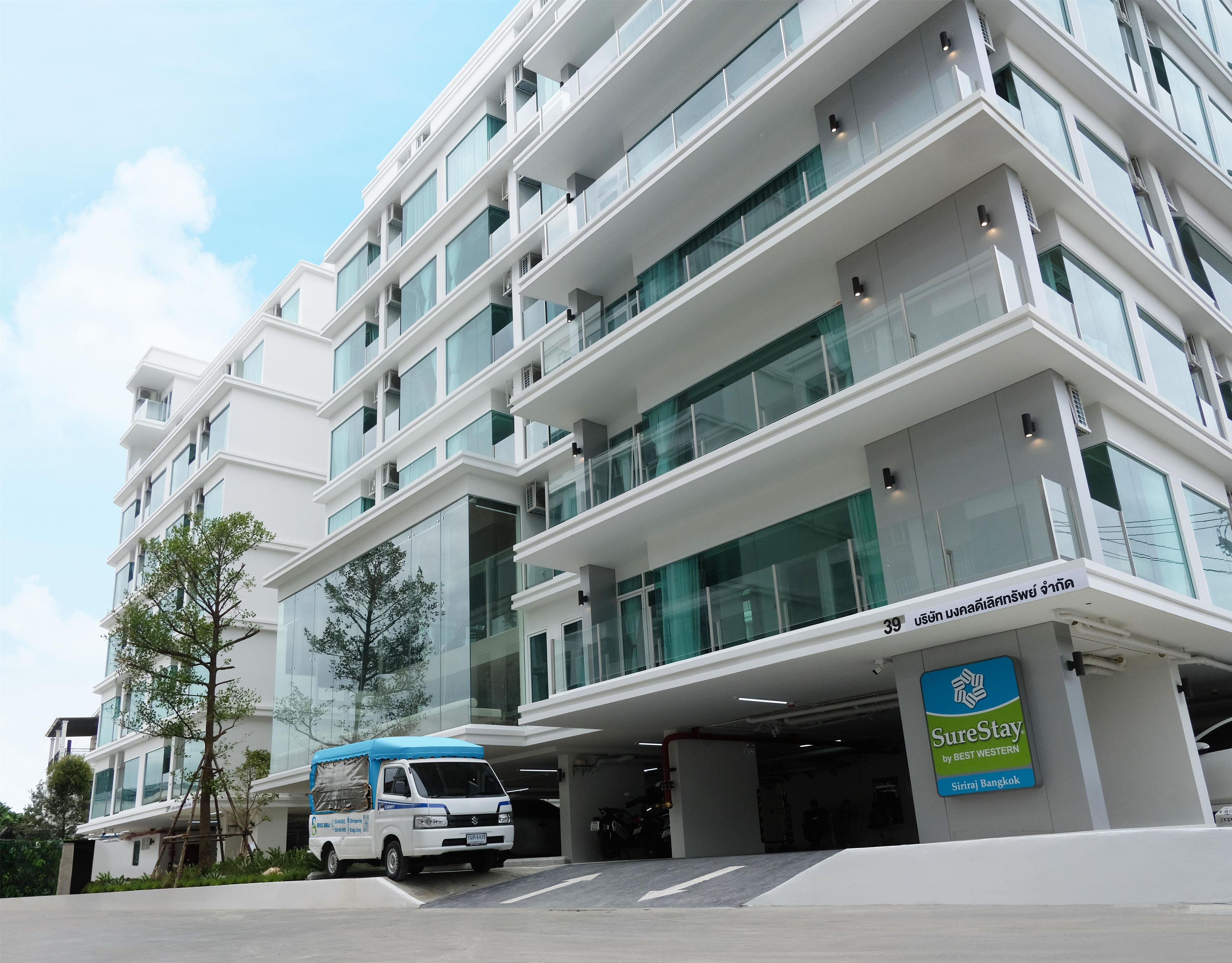Un hôtel à plusieurs étages au design moderne, doté d’un parking couvert et d’une enseigne « SureStay by BEST WESTERN ».