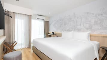 A hotel room with a large bed, a desk, a chair, and a wall-mounted TV.