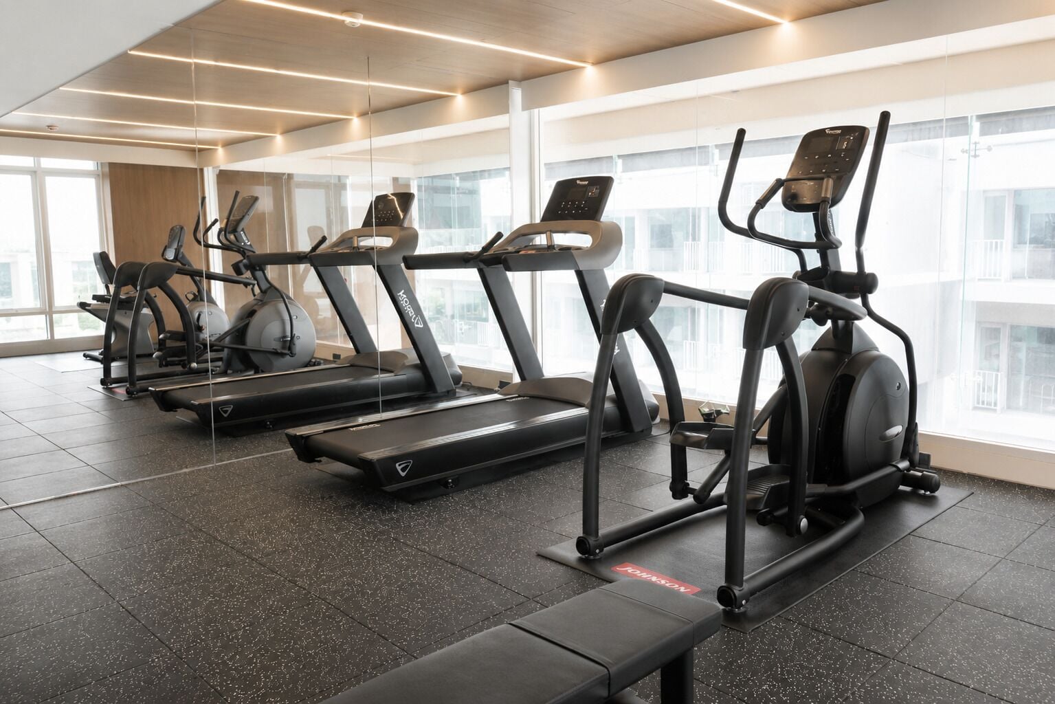 A gym with treadmills, ellipticals, and a bench.