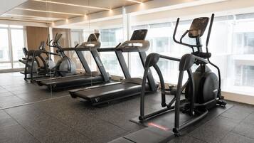 A gym with treadmills, ellipticals, and a bench.