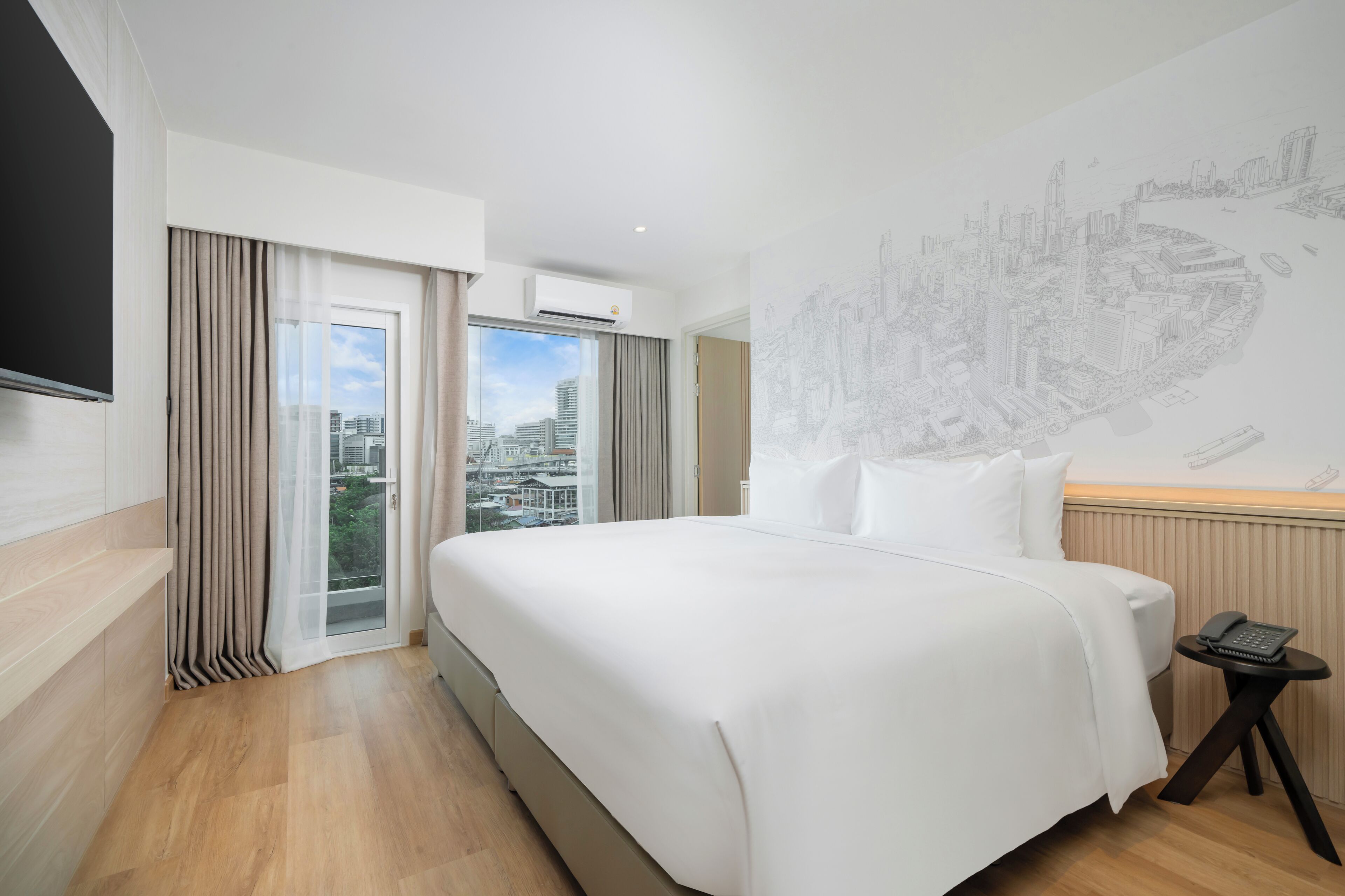 Habitación de hotel con una cama grande, vista panorámica de la ciudad a través de la ventana y una obra de arte colgada en la pared.