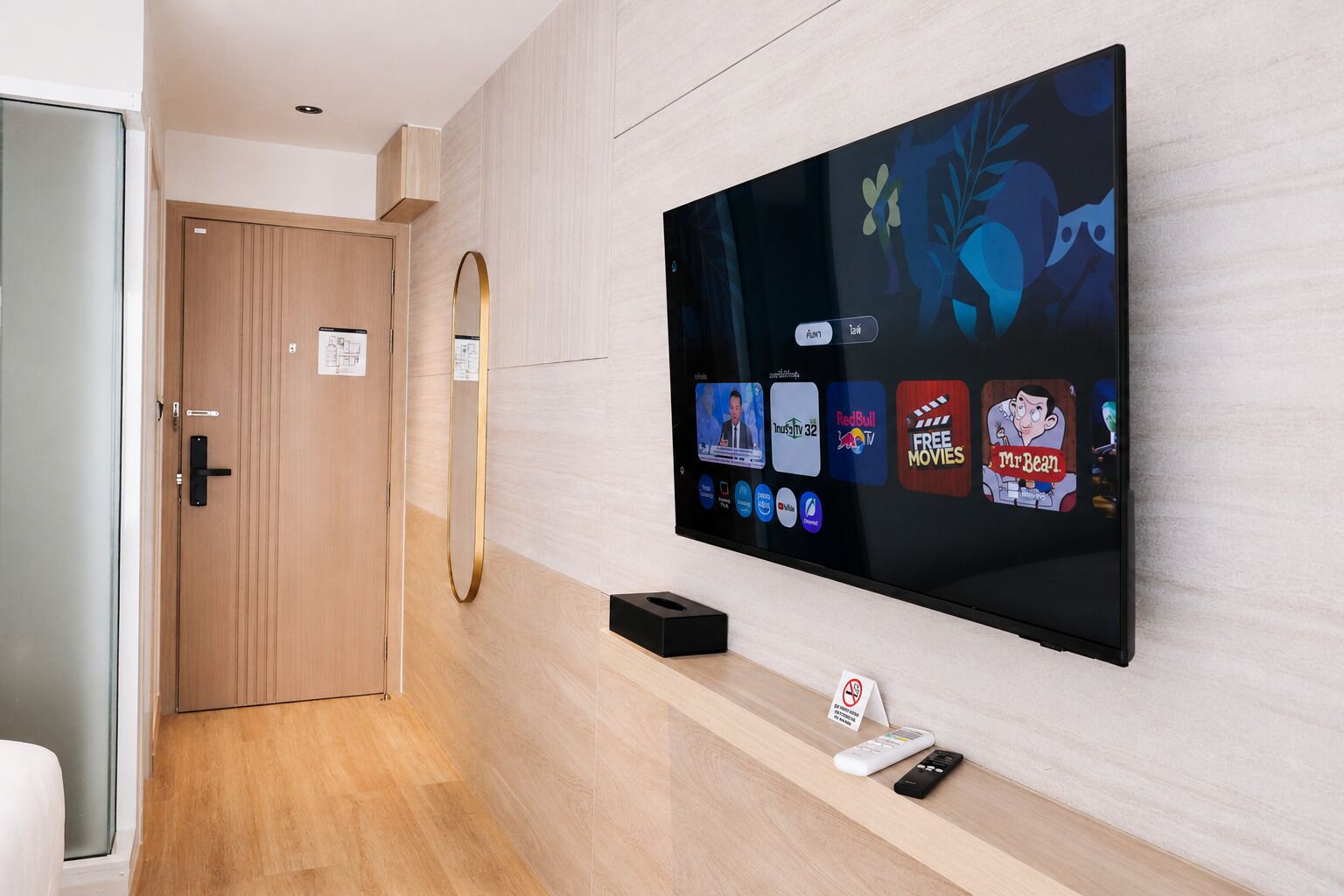 A modern hotel room with a large flat-screen TV mounted on the wall displaying various streaming services.
