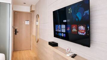 A modern hotel room with a large flat-screen TV mounted on the wall displaying various streaming services.