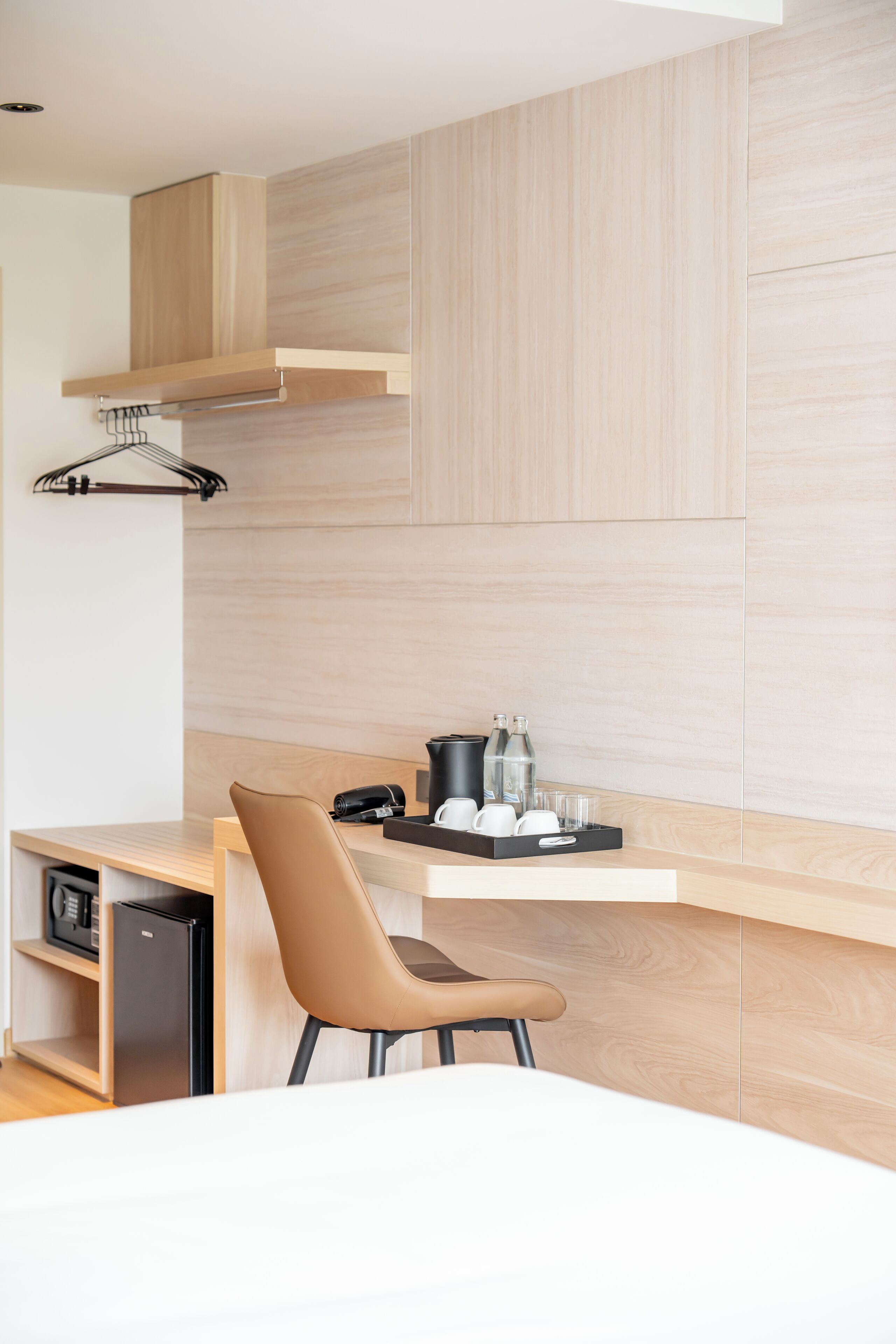Una habitación de hotel moderna con escritorio de madera, una silla, cama y zona de kitchenette.